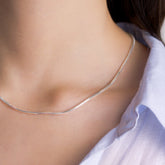 Fine jewellery, silver jewellery, hypoallergenic, tarnish-free. Front view close up of Silver snake chain necklace on a person wearing a blue shirt